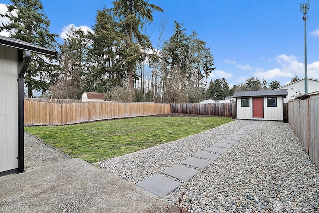 view of yard with a storage shed, an outbuilding, and a fenced backyard