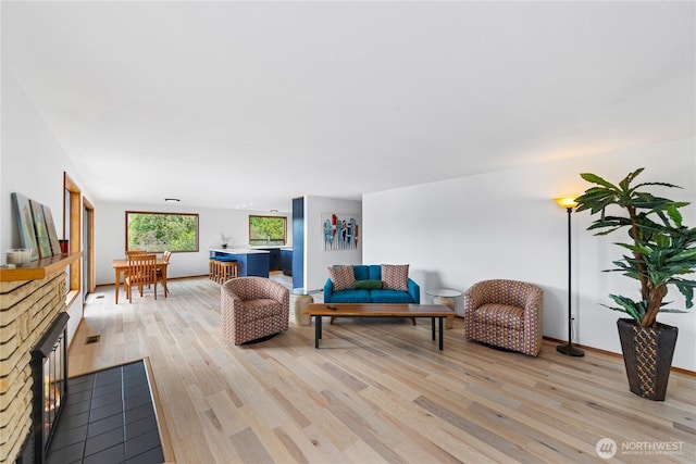 living area with a stone fireplace and light wood finished floors