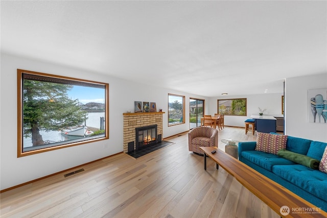 living area featuring visible vents, a brick fireplace, and light wood-style floors