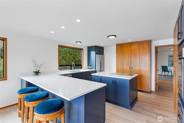 kitchen featuring a sink, a kitchen bar, plenty of natural light, and freestanding refrigerator