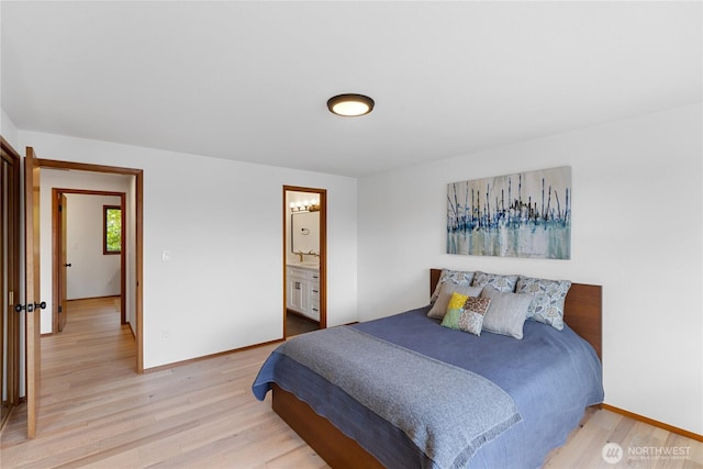 bedroom with connected bathroom, light wood-type flooring, and baseboards