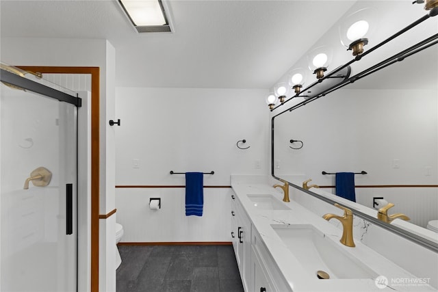 full bathroom with wainscoting, toilet, and a sink