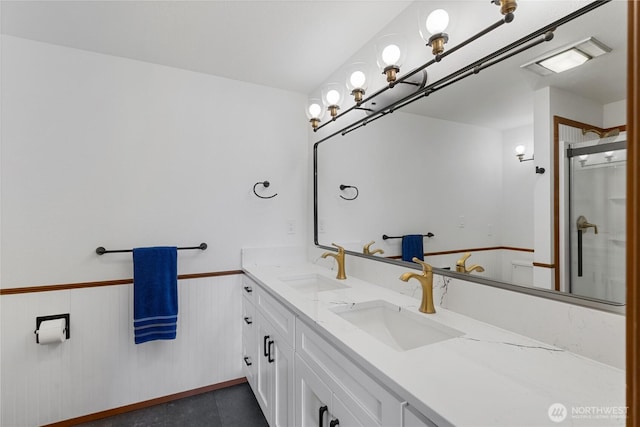 bathroom with double vanity, visible vents, a wainscoted wall, and a sink