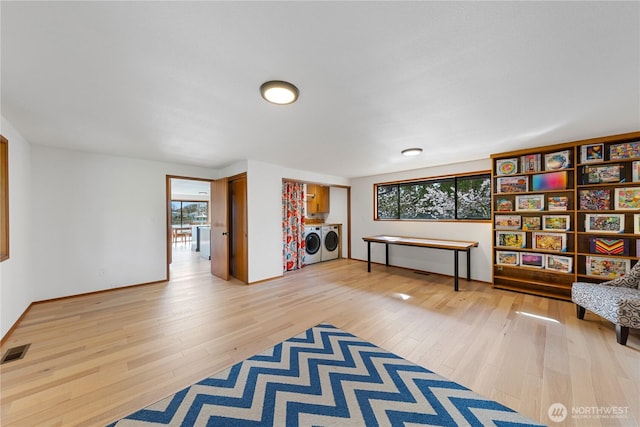 living area featuring a wealth of natural light, visible vents, washing machine and dryer, and light wood finished floors