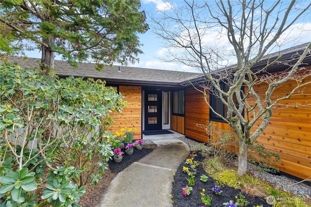 doorway to property with a shingled roof