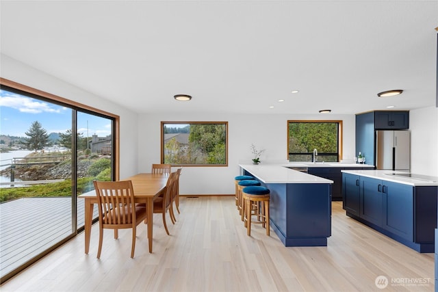 interior space featuring a peninsula, a breakfast bar, light countertops, and freestanding refrigerator