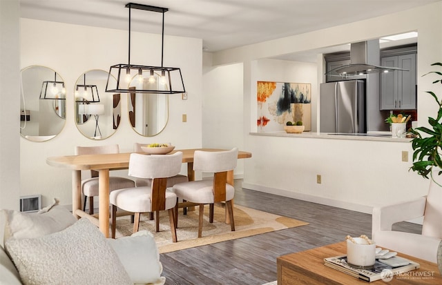 dining room with a notable chandelier, wood finished floors, and baseboards