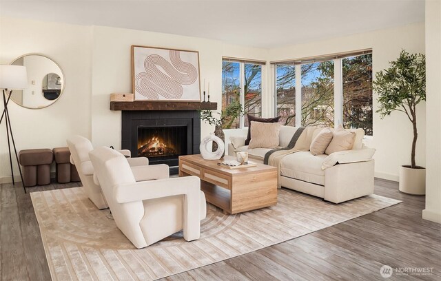 living room featuring a warm lit fireplace and wood finished floors