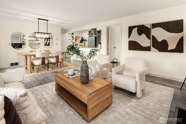 living area featuring wood finished floors, visible vents, and baseboards