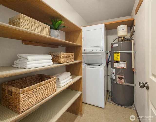 laundry area with laundry area, strapped water heater, stacked washer and dryer, and light floors