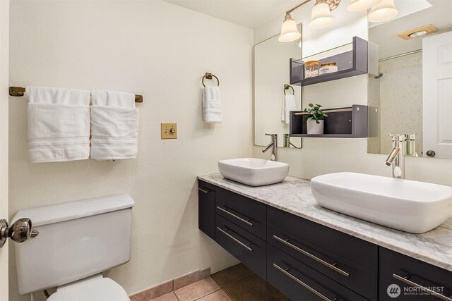 bathroom with tile patterned floors, toilet, double vanity, and a sink