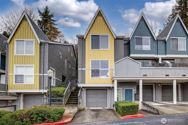 townhome / multi-family property featuring board and batten siding, stairs, a garage, and driveway