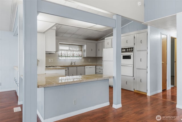 1402 22nd St NE Unit 402, Auburn, WA 98002 - kitchen with white appliances, dark wood finished floors, a peninsula, backsplash, and tile counters