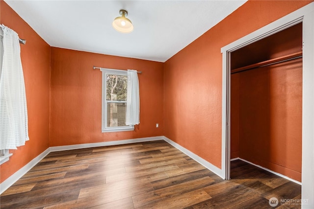 unfurnished bedroom with a closet, baseboards, and wood finished floors