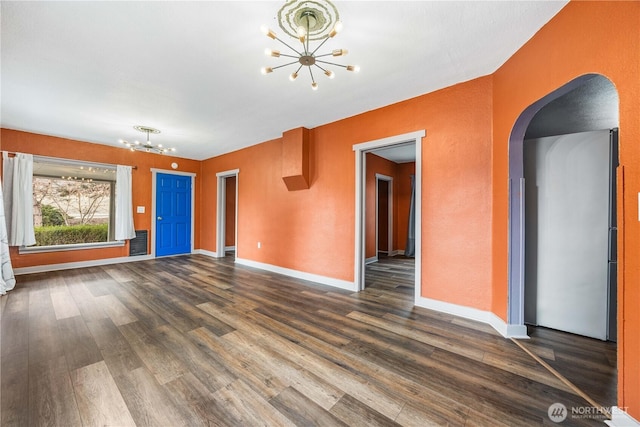 unfurnished living room featuring baseboards, arched walkways, a chandelier, and dark wood-style flooring