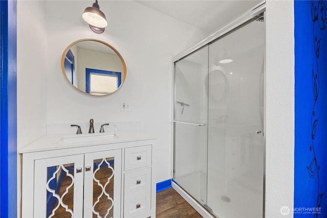 full bathroom with wood finished floors, a stall shower, and vanity