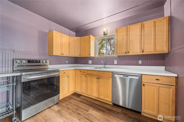 kitchen featuring light brown cabinetry, appliances with stainless steel finishes, light countertops, and a sink