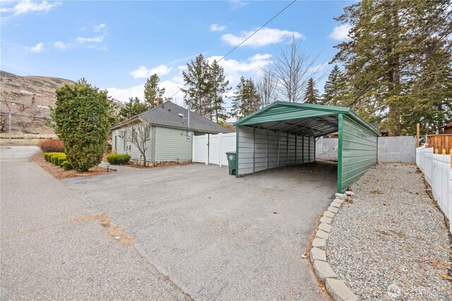 view of car parking featuring a carport, driveway, and fence