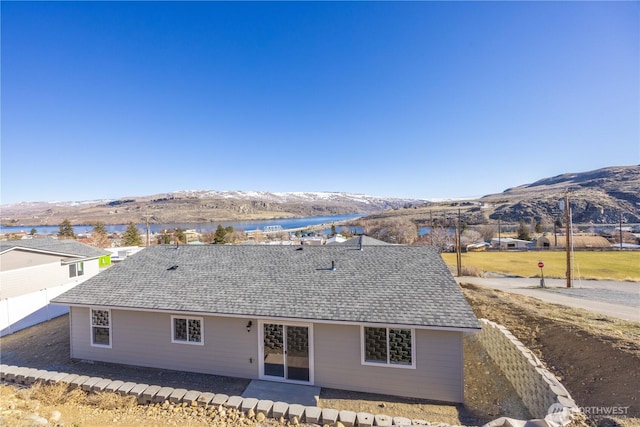 back of property with a patio area, a mountain view, and a shingled roof