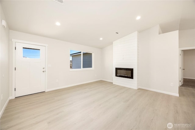 unfurnished living room featuring lofted ceiling, light wood-style flooring, recessed lighting, a fireplace, and baseboards