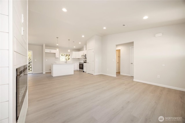 unfurnished living room with recessed lighting, a large fireplace, light wood-style floors, and vaulted ceiling