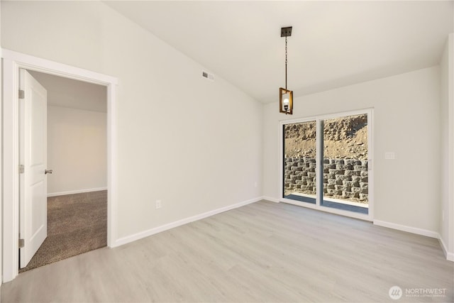empty room with vaulted ceiling, visible vents, baseboards, and wood finished floors