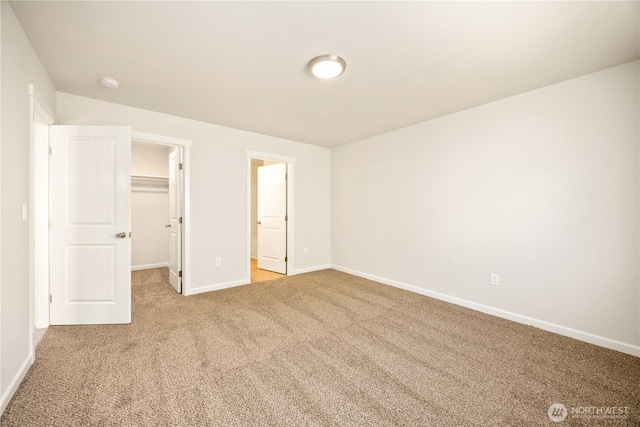 unfurnished bedroom with a walk in closet, carpet flooring, baseboards, and a closet