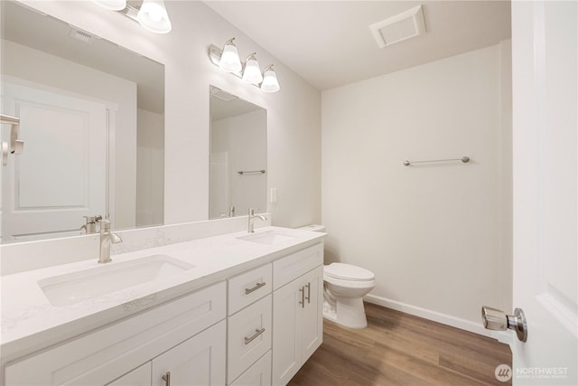 full bathroom featuring visible vents, toilet, wood finished floors, and a sink