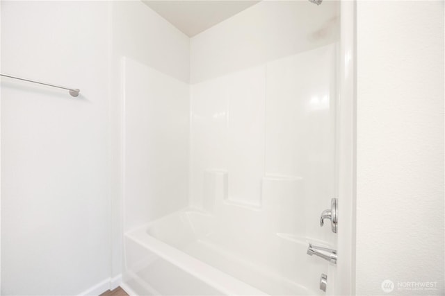 bathroom featuring bathing tub / shower combination and baseboards
