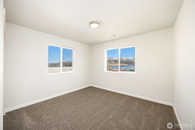 empty room featuring visible vents, baseboards, and dark carpet