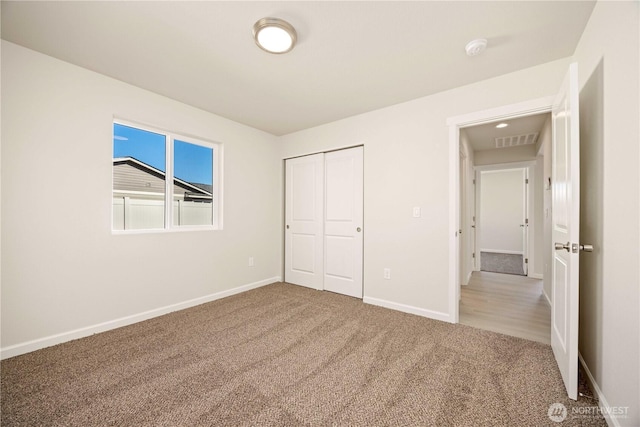 unfurnished bedroom with a closet, visible vents, carpet flooring, and baseboards