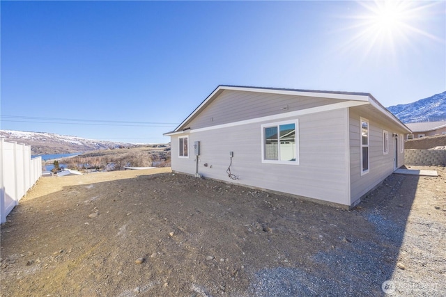 rear view of house featuring a mountain view and fence