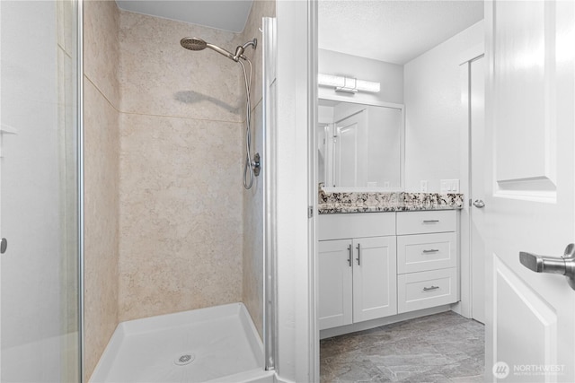 bathroom with vanity, a shower stall, and a textured ceiling