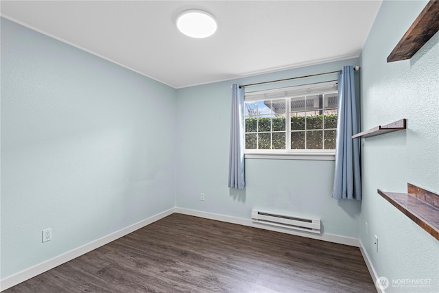 empty room featuring a baseboard heating unit, wood finished floors, and baseboards