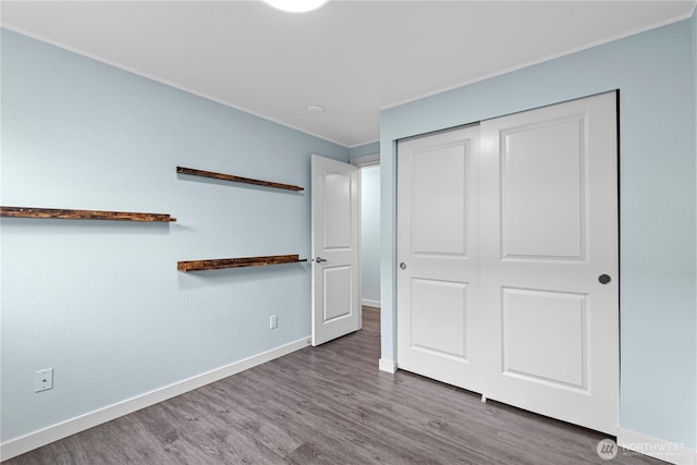 unfurnished bedroom featuring a closet, baseboards, and wood finished floors