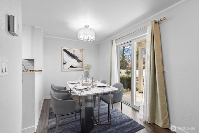 dining space with wood finished floors, baseboards, a chandelier, and ornamental molding