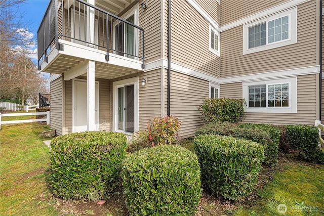 view of side of property with a yard and a balcony