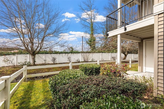 view of yard featuring a balcony and a fenced backyard