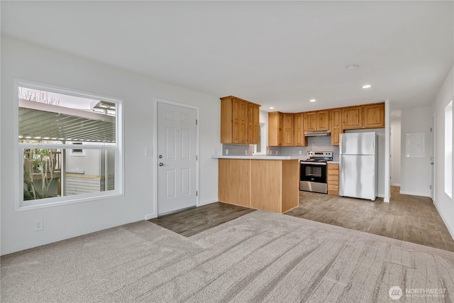 kitchen featuring a peninsula, recessed lighting, stainless steel appliances, light countertops, and under cabinet range hood