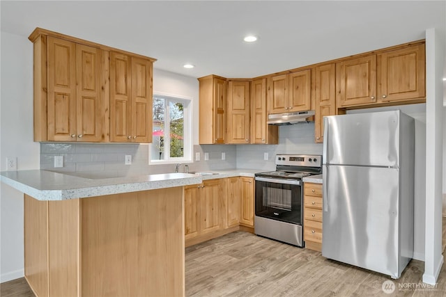 kitchen featuring under cabinet range hood, appliances with stainless steel finishes, light countertops, and light wood-style floors