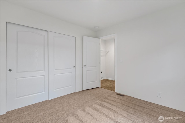 unfurnished bedroom with a closet, visible vents, and carpet floors