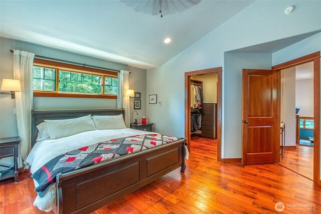 bedroom with wood finished floors, a spacious closet, recessed lighting, a closet, and high vaulted ceiling
