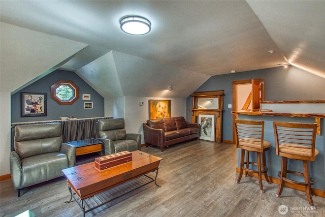living area with vaulted ceiling, baseboards, and wood finished floors