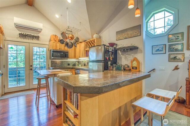 kitchen featuring appliances with stainless steel finishes, an AC wall unit, high vaulted ceiling, a peninsula, and dark countertops