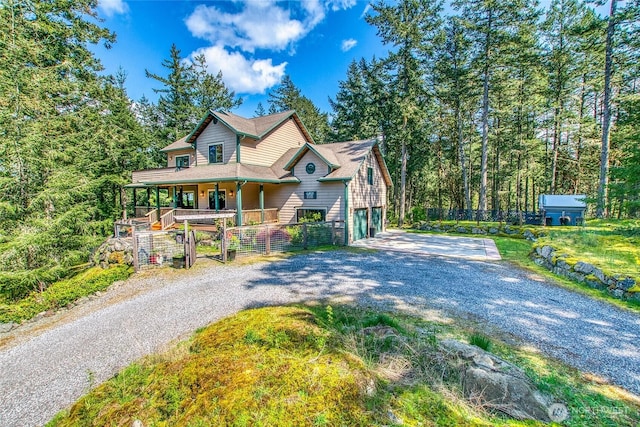 view of front facade featuring driveway, a porch, a garage, and fence