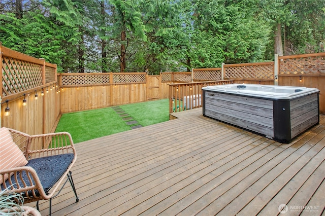 wooden terrace with a lawn, a hot tub, and a fenced backyard