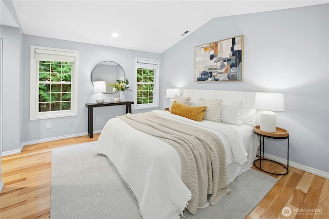 bedroom featuring visible vents, wood finished floors, baseboards, and vaulted ceiling