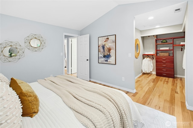 bedroom with vaulted ceiling, light wood-style flooring, baseboards, and a closet