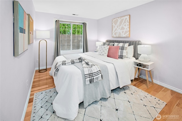 bedroom with visible vents, baseboards, and wood finished floors