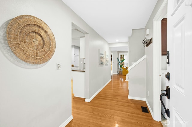 entryway with light wood finished floors, visible vents, stairs, and baseboards